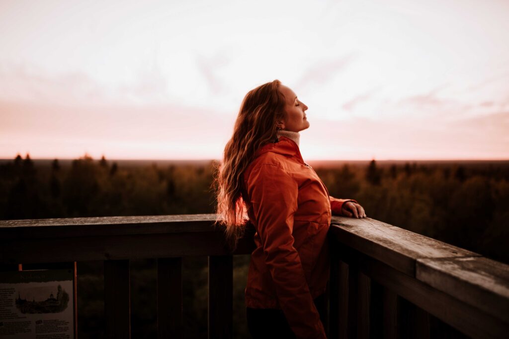 nainen nauttii auringonlaskusta luonnossa